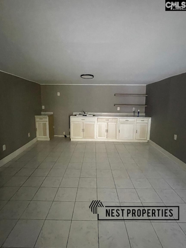 interior space with a sink, baseboards, and light tile patterned flooring