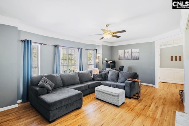 living room featuring baseboards, ceiling fan, and light wood finished floors