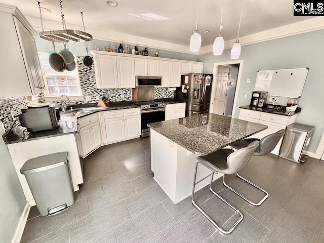 kitchen with a kitchen island, decorative light fixtures, decorative backsplash, appliances with stainless steel finishes, and a sink