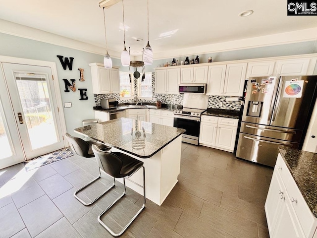 kitchen featuring a breakfast bar, pendant lighting, a sink, appliances with stainless steel finishes, and decorative backsplash