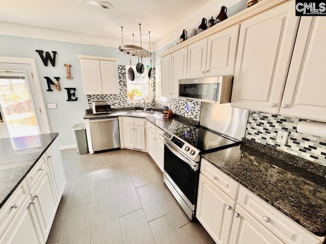 kitchen featuring a sink, backsplash, appliances with stainless steel finishes, and dark stone countertops