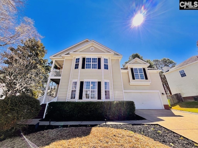 traditional-style home with a balcony, concrete driveway, and an attached garage