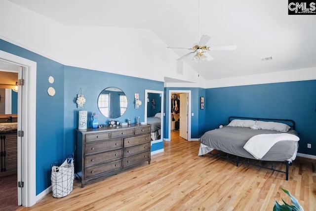 bedroom featuring a spacious closet, visible vents, vaulted ceiling, wood finished floors, and a closet