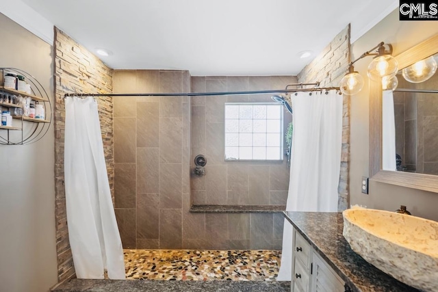 full bathroom featuring a tile shower and vanity