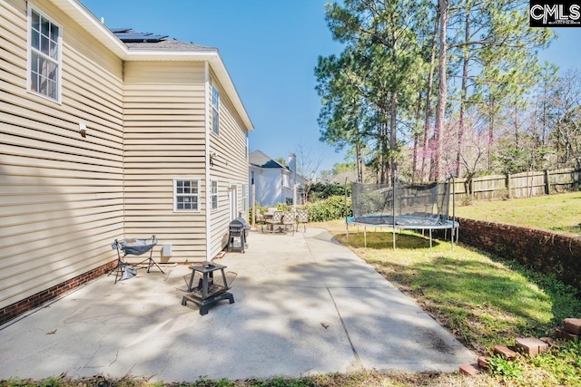 view of patio / terrace with grilling area, a trampoline, and fence