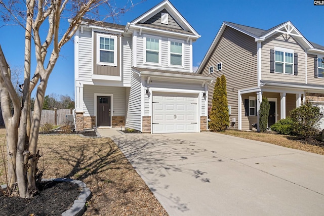 craftsman-style home featuring stone siding, an attached garage, driveway, and fence