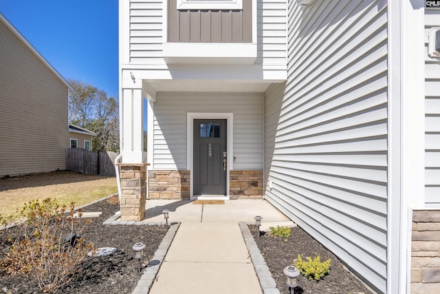 property entrance featuring fence and stone siding