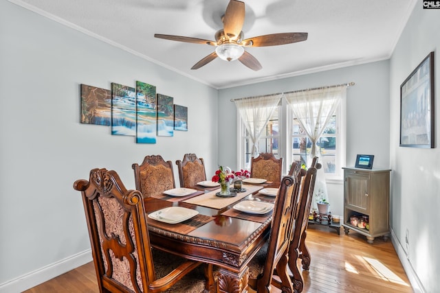 dining space featuring baseboards, light wood-style flooring, a ceiling fan, and ornamental molding