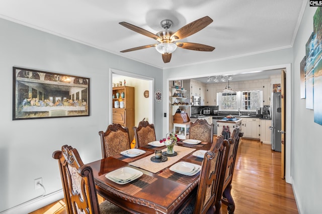 dining area with crown molding, light wood-style flooring, and ceiling fan