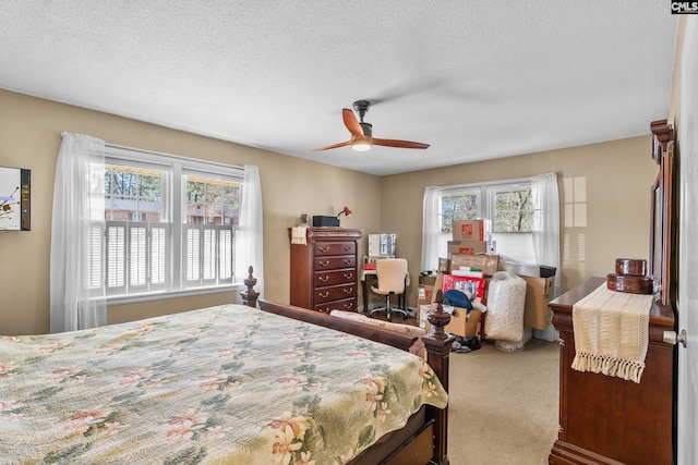 bedroom with multiple windows, a textured ceiling, ceiling fan, and carpet flooring