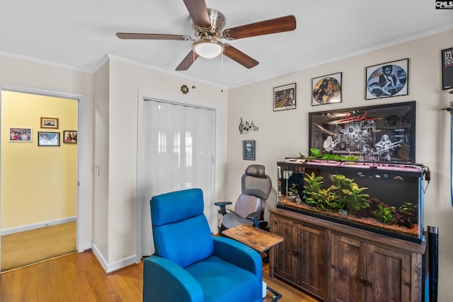 living area with baseboards, a ceiling fan, light wood-style floors, and ornamental molding