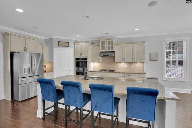 kitchen with cream cabinetry, a sink, light stone counters, dark wood-style floors, and appliances with stainless steel finishes