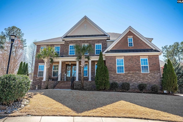 view of front of house featuring a standing seam roof, a porch, brick siding, and metal roof