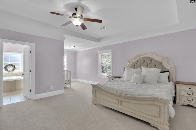 bedroom featuring light carpet, visible vents, multiple windows, and a tray ceiling