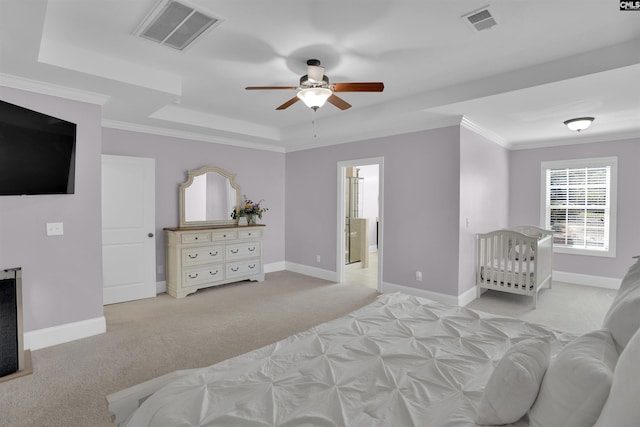 bedroom with light carpet, visible vents, a raised ceiling, and baseboards