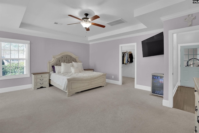 bedroom with visible vents, light colored carpet, baseboards, and a tray ceiling