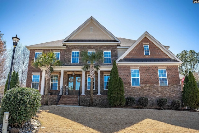 view of front of house with a standing seam roof, french doors, covered porch, metal roof, and brick siding