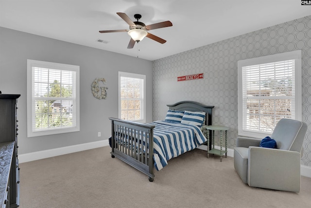 carpeted bedroom featuring wallpapered walls, baseboards, visible vents, and a ceiling fan