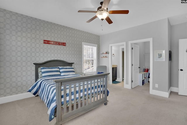 bedroom featuring baseboards, an accent wall, and wallpapered walls