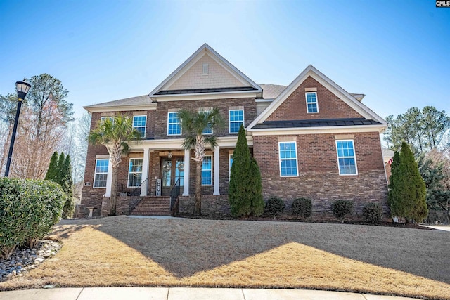 craftsman house with a standing seam roof, a porch, brick siding, and metal roof