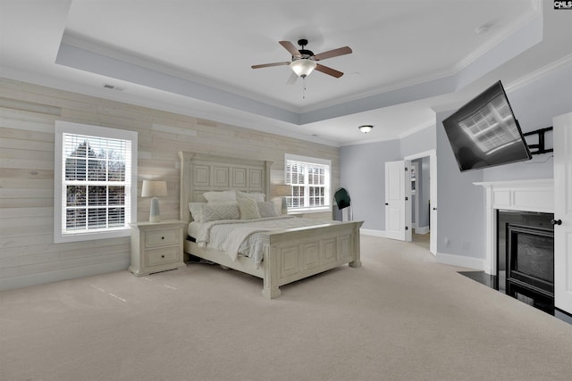 bedroom with a tray ceiling, multiple windows, and light carpet