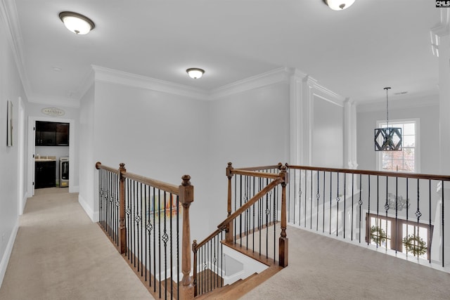 hall with an upstairs landing, carpet, an inviting chandelier, and crown molding