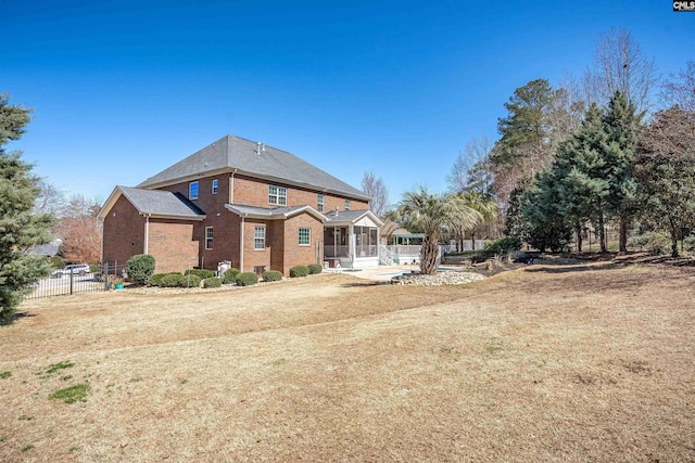 back of house with fence, brick siding, a sunroom, and a lawn