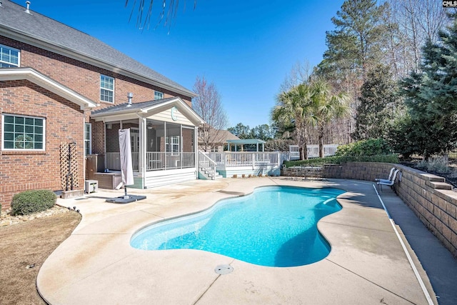 view of pool with a fenced in pool, fence, a wooden deck, a sunroom, and a patio