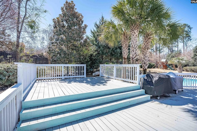 wooden deck featuring grilling area and a pool