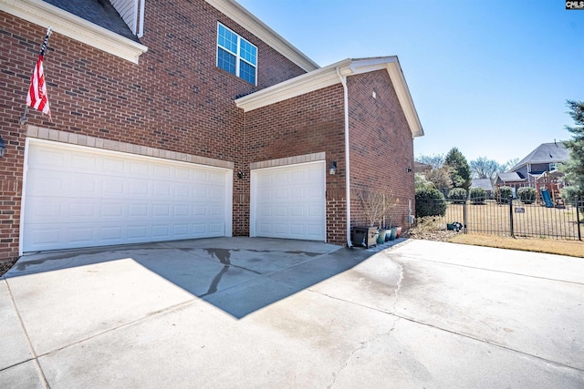 view of side of home featuring brick siding, concrete driveway, a garage, and fence