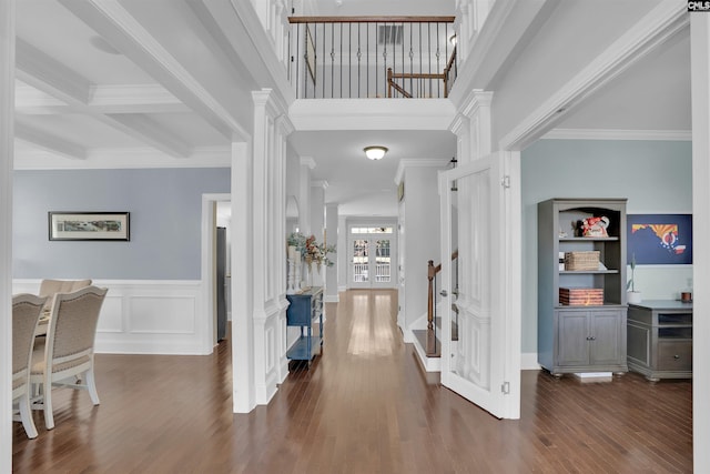 corridor featuring beam ceiling, crown molding, decorative columns, and wood finished floors