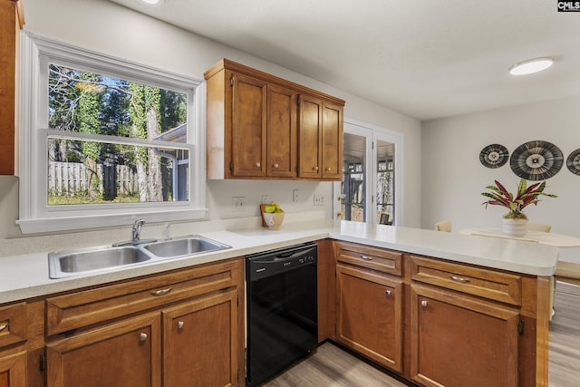 kitchen with a peninsula, black dishwasher, light countertops, and a sink