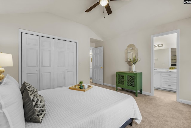 bedroom with baseboards, lofted ceiling, a closet, light colored carpet, and connected bathroom