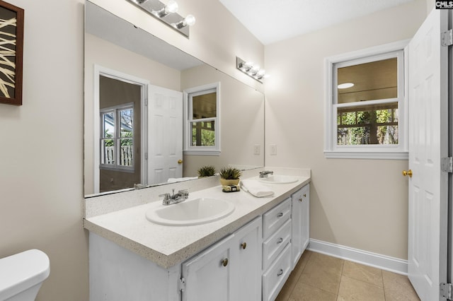 bathroom featuring a sink, baseboards, and plenty of natural light