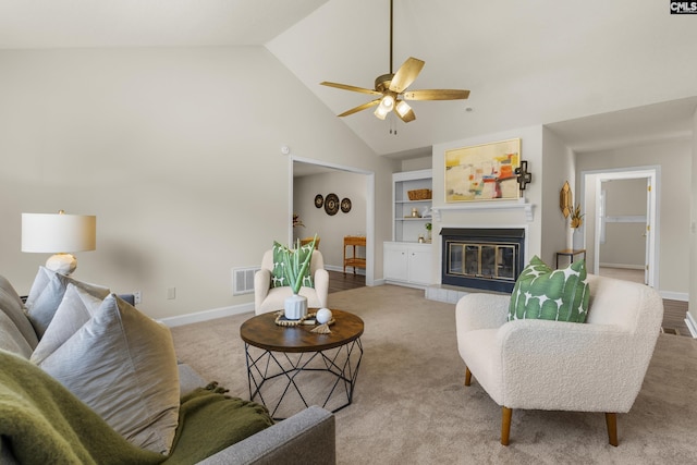 living area with visible vents, built in shelves, baseboards, and a glass covered fireplace