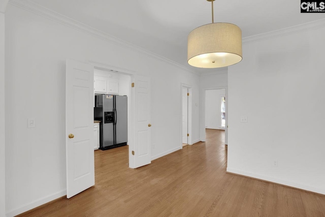 unfurnished room featuring baseboards, ornamental molding, and light wood finished floors