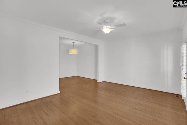 spare room with baseboards, wood finished floors, ceiling fan, and ornamental molding