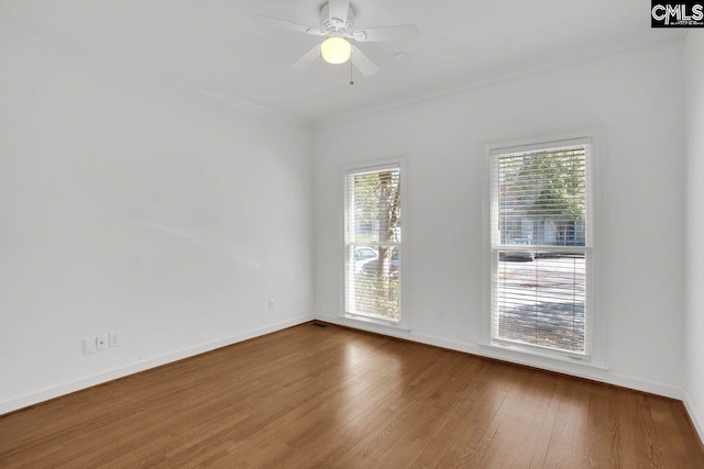 empty room with ornamental molding, a ceiling fan, baseboards, and wood finished floors