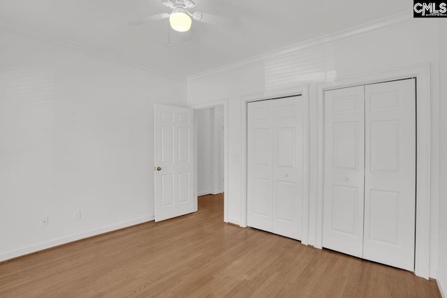 unfurnished bedroom featuring light wood finished floors, two closets, crown molding, and baseboards