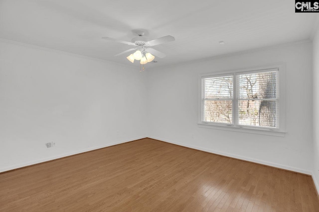 spare room with a ceiling fan, crown molding, baseboards, and wood finished floors