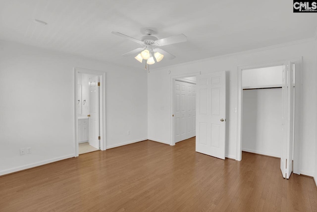 unfurnished bedroom with two closets, a ceiling fan, baseboards, and wood finished floors