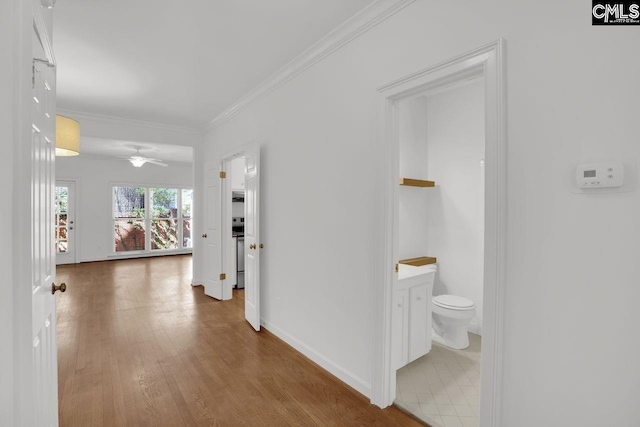 corridor with crown molding, wood finished floors, and baseboards