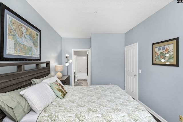 bedroom featuring baseboards and connected bathroom