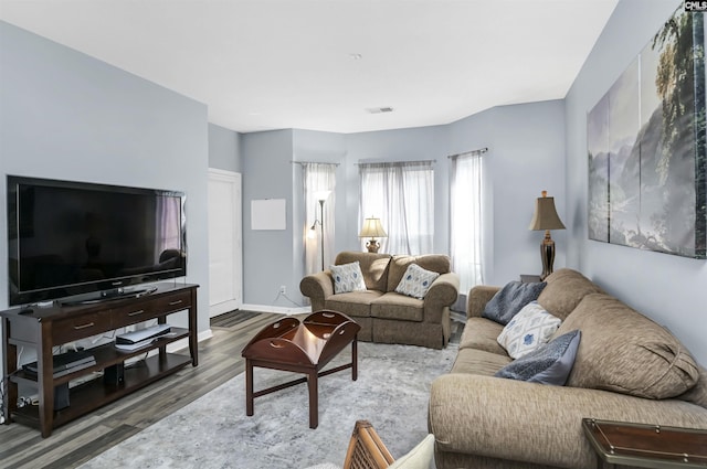 living area with wood finished floors, visible vents, and baseboards