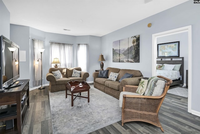 living room with visible vents, baseboards, and dark wood-style floors