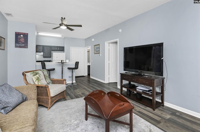 living area featuring dark wood finished floors, a ceiling fan, visible vents, and baseboards