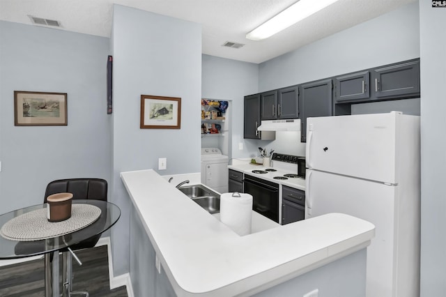 kitchen featuring visible vents, washer / dryer, freestanding refrigerator, electric range, and a sink