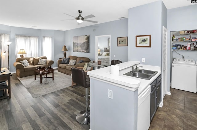 kitchen with a kitchen bar, a sink, washer / clothes dryer, light countertops, and dishwasher