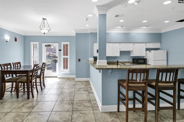 kitchen featuring ornamental molding, white cabinetry, freestanding refrigerator, black microwave, and baseboards