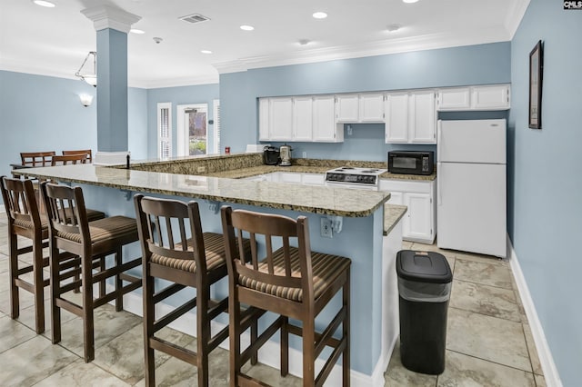 kitchen with visible vents, crown molding, a breakfast bar, white cabinets, and white appliances